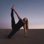 woman holding her left leg high kneeling on floor
