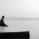 Man zit alleen aan water, serene sfeer, zwart-wit foto