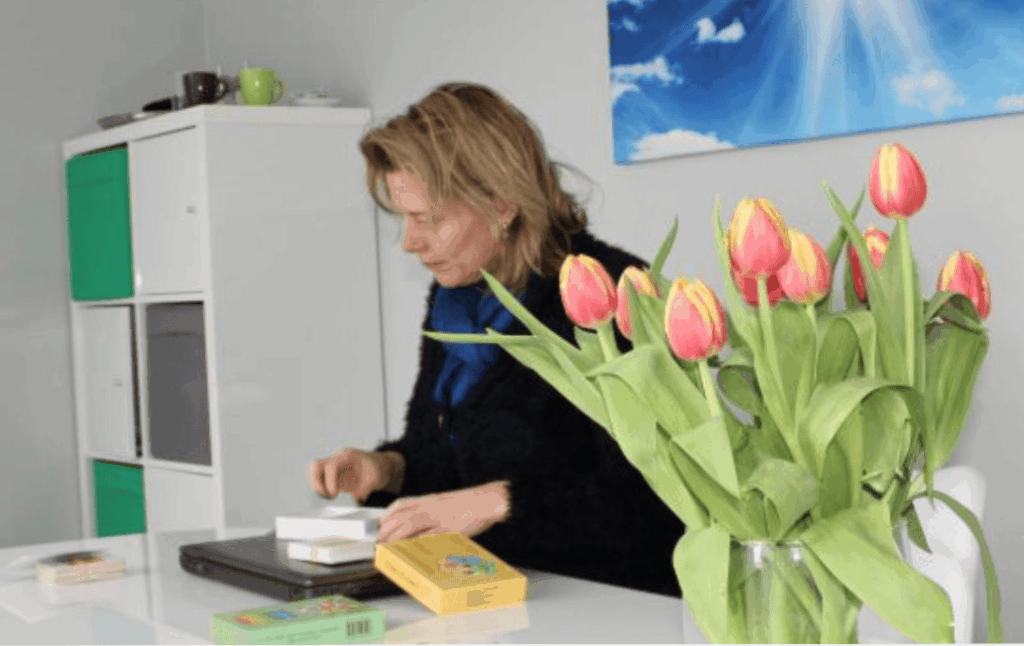 Vrouw aan bureau met tulpen en laptop, moderne kantooromgeving