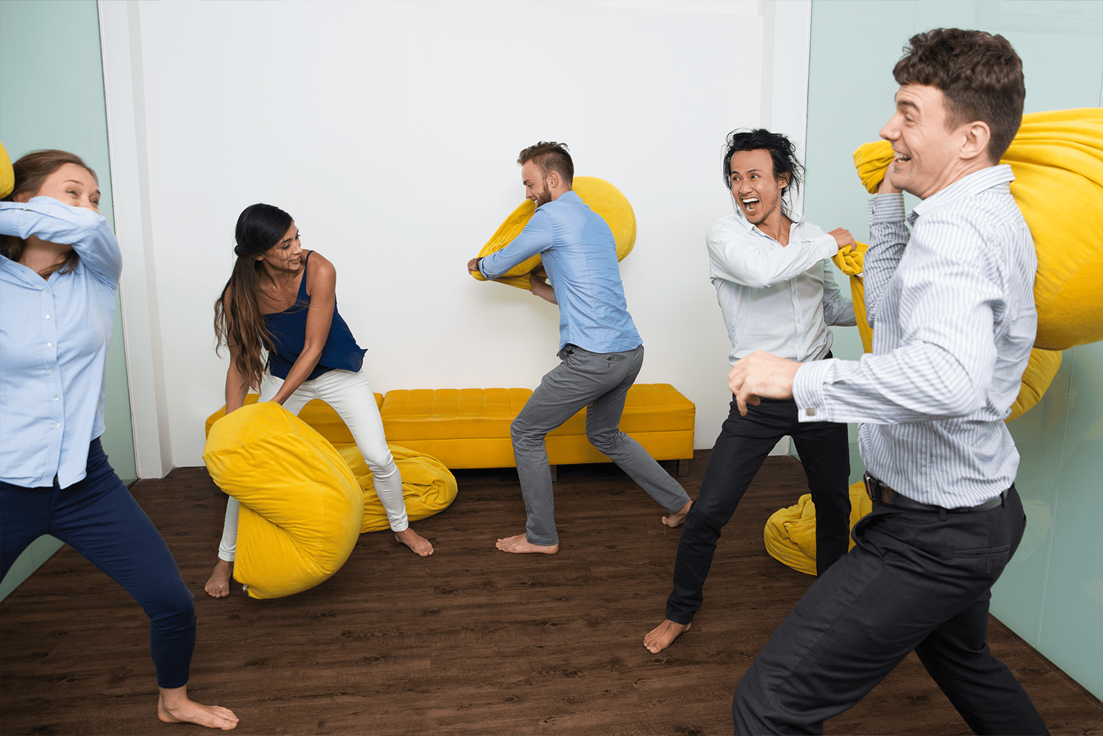 Vijf mensen houden een kussengevecht in een kantooromgeving